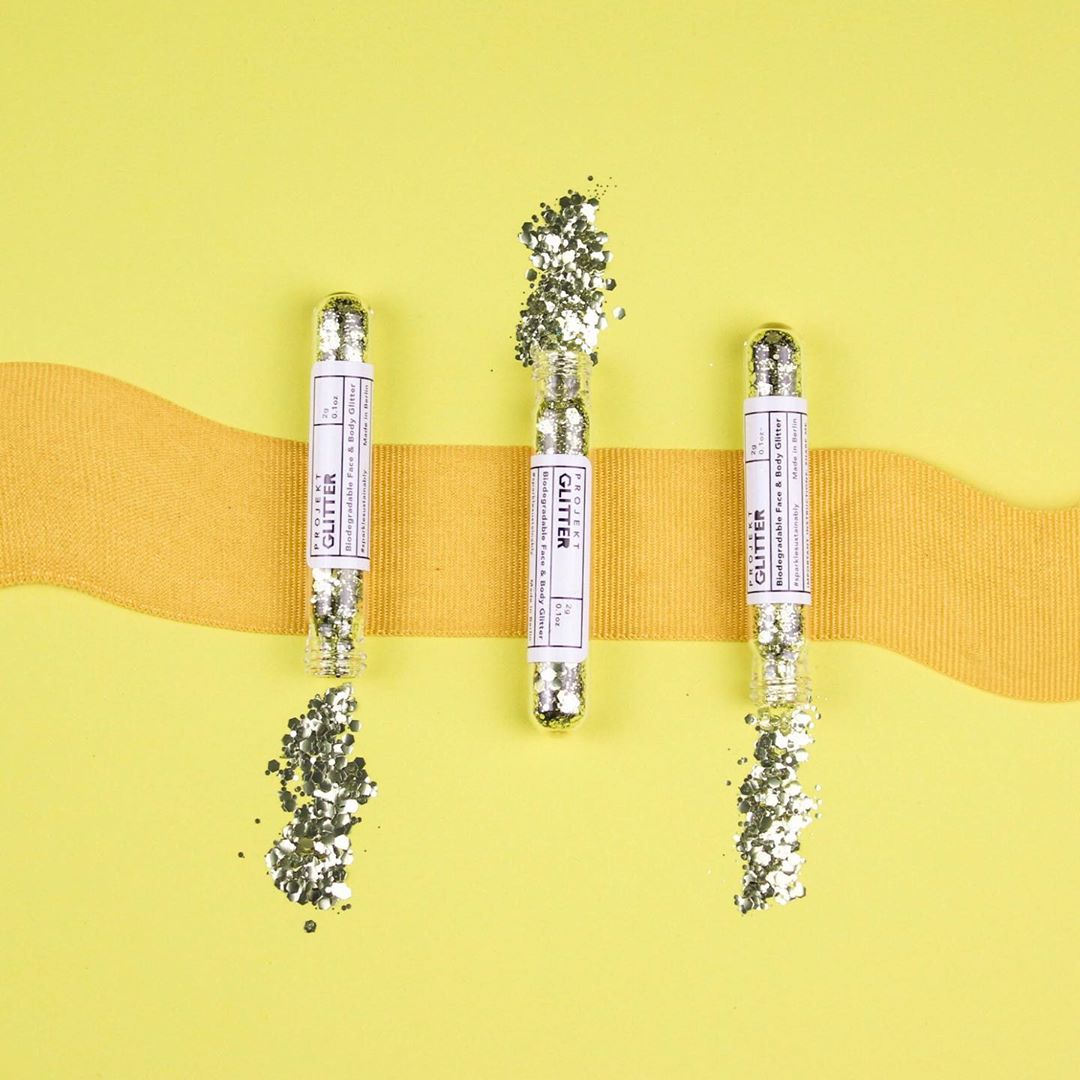 3 tubes of open silver glitter on a yellow background