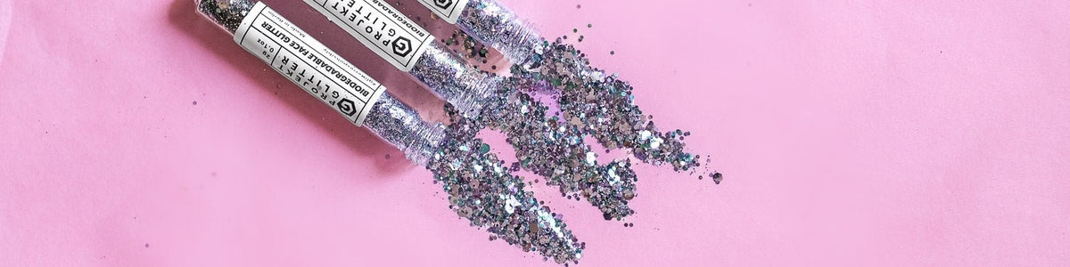 3 opened tubes of glitter against a pink background