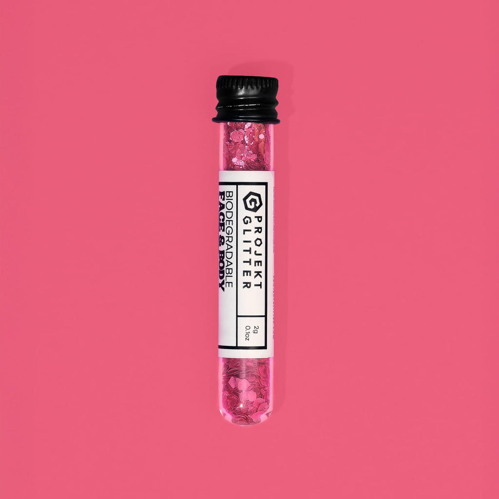 Test tube with pink glitter labeled 'Projekt Glitter' on a red background