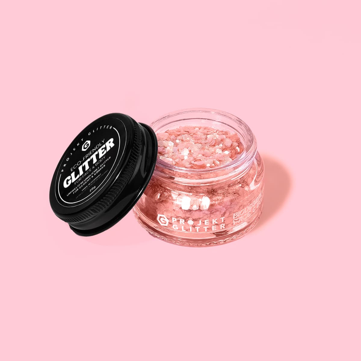 Jar of glitter with black lid on a pink background